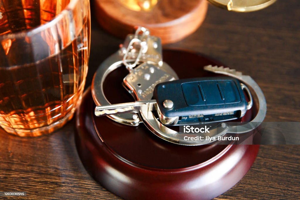 Drinking alcohol on driving ability The concept of a DUI. Law hammer, alcohol and car keys on wooden table, dark background Driving Under The Influence Stock Photo