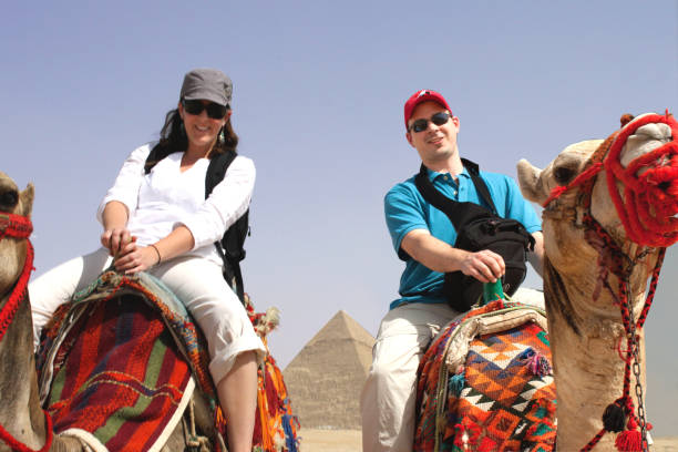 istock Camel in dessert 2 people riding them trip 1203034014
