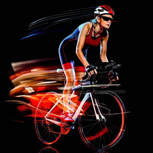 one caucasian woman triathlon triathlete cyclist cycling studio shot  isolated on black background with light painting effect