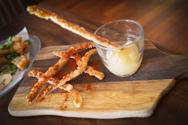 Tasty pork crackling strips and an apple sauce dip in a glass on a wooden board served as a snack or appetiser Tasty pork crackling strips and an apple sauce dip in a glass on a wooden board served as a snack or appetiser appetiser stock pictures, royalty-free photos & images