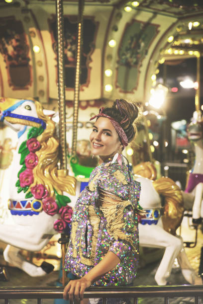 Stylish woman wearing sequin jacket on the carousel in theme park