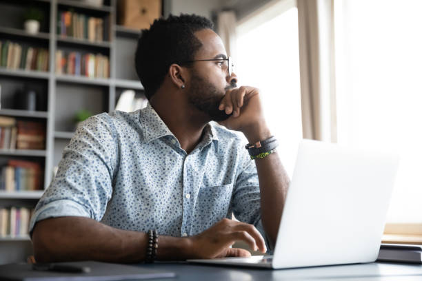 istock Thoughtful serious african man sit with laptop thinking of project 1203044187