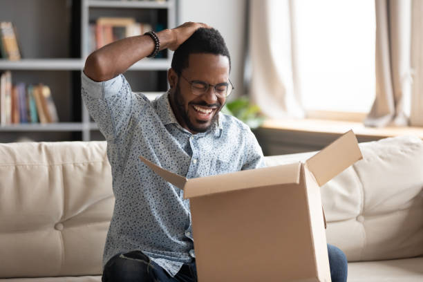 istock Happy african male customer hold cardboard box open post parcel 1203044204