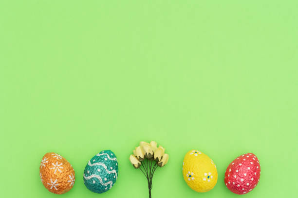 istock Colorful painted orange, blue, red and yellow Easter eggs with yellow spring flowers on green background. Happy Easter holiday concept. Flat lay style with copy space. 1203045803