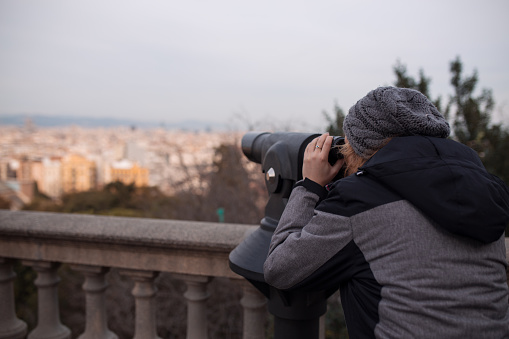 Woman tourist watching the cityscape through binoculars