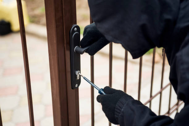 istock Thief breaking lock to open the gate. Male thief trying to open gate, closeup. 1203050383