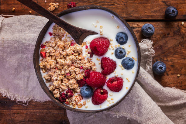 yogurt bowl with granola, blueberries and raspberries - quinoa spoon wood photography imagens e fotografias de stock