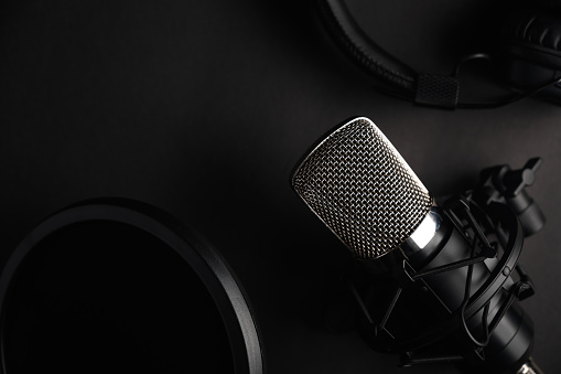 Black studio microphone on a black background with a pop filter with space for design, baner with space