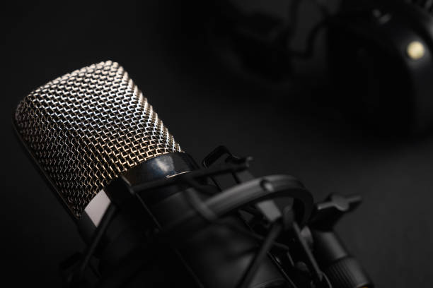 istock Studio black studio microphone with studio headphones on a black background. Banner. Radio, work with sound, podcasts. 1203054877