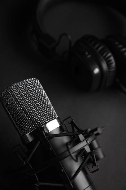 Microphone for podcasts and studio headphones on a black background, vertical frame