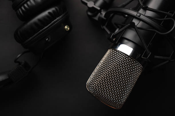 istock Studio black studio microphone with studio headphones on a black background. Banner. Radio, work with sound, podcasts. 1203054917