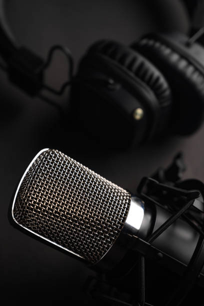 istock Microphone for podcasts and studio headphones on a black background, vertical frame 1203054932