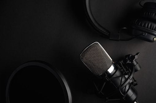 Black studio microphone on a black background with a pop filter with space for design, baner with space