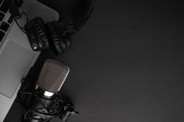 istock Studio black studio microphone with studio headphones on a laptop on a black background. Banner. Radio, work with sound, podcasts, blogging. 1203055222