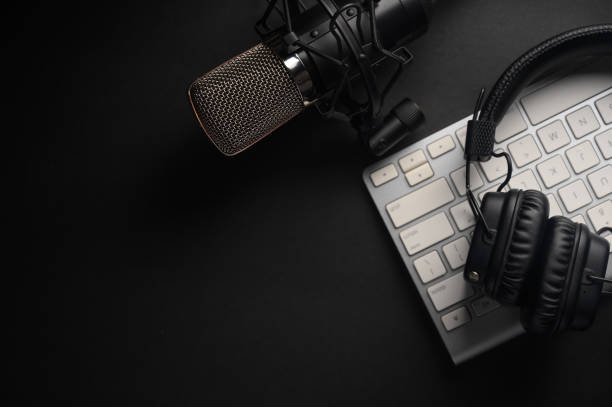 istock Flat lay, Studio microphone with professional headphones on a PC keyboard. Black on a black background. Podcasts, radio, streams, blogging, working with sound, recording tracks 1203055237