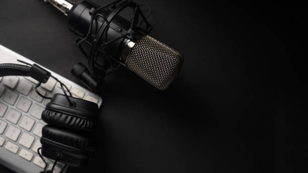 istock Flat lay, Studio microphone with professional headphones on a PC keyboard. Black on a black background. Podcasts, radio, streams, blogging, working with sound, recording tracks 1203055752