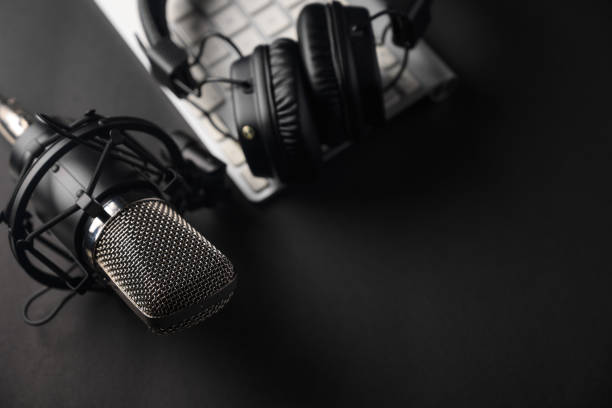 istock Flat lay, Studio microphone with professional headphones on a PC keyboard. Black on a black background. Podcasts, radio, streams, blogging, working with sound, recording tracks 1203055771