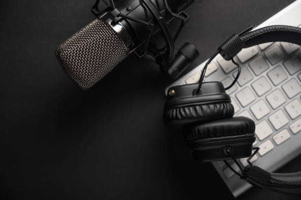 flat lay, studio microphone with professional headphones on a pc keyboard. black on a black background. podcasts, radio, streams, blogging, working with sound, recording tracks - industrial equipment audio imagens e fotografias de stock