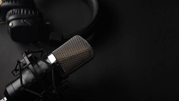 istock Studio black studio microphone with studio headphones on a black background. Banner. Radio, work with sound, podcasts. 1203056327