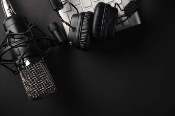 istock Flat lay, Studio microphone with professional headphones on a PC keyboard. Black on a black background. Podcasts, radio, streams, blogging, working with sound, recording tracks 1203056340