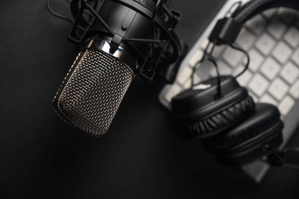 istock Microphone for podcasts and studio headphones on a PC keyboard on a black background, horizontal frame 1203056354