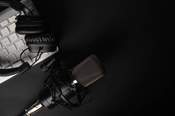istock Flat lay, Studio microphone with professional headphones on a PC keyboard. Black on a black background. Podcasts, radio, streams, blogging, working with sound, recording tracks 1203056371