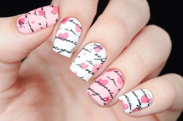 Photo of Pink white manicure on St. Valentine s Day with pattern words letter and hearts