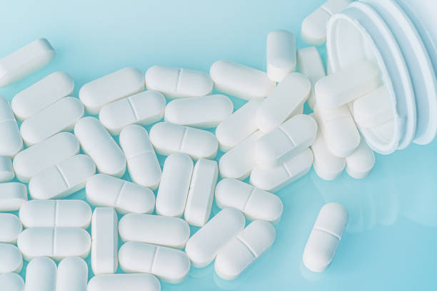 istock White medicine tablets spilled on table from pill bottle. Medications drugs or supplements or opioid addiction from pain killers, top view 1203067445