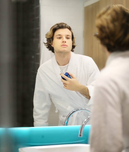 istock young man looking in the mirror,combing his hair,looking at problems on face 1203067487