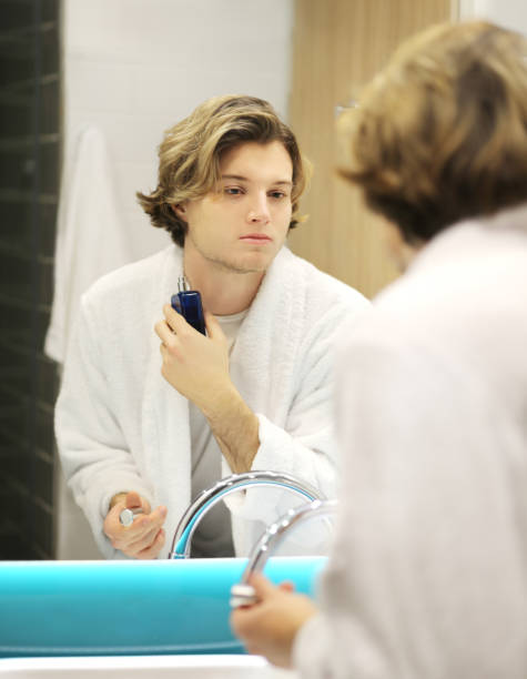 istock young man looking in the mirror,combing his hair,looking at problems on face 1203067527