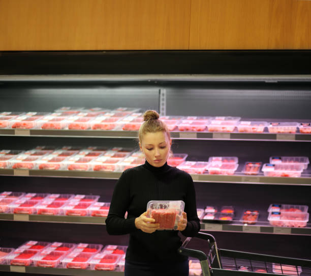 mujer comprando un paquete de carne en el supermercado - supermarket meat women packaging fotografías e imágenes de stock