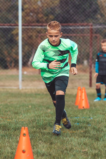 istock Kid player in soccer jersey running between cones and ring ladder marker 1203069094