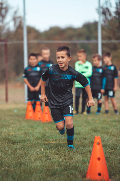 istock Kid soccer player running between cones and ring ladder marker 1203069101
