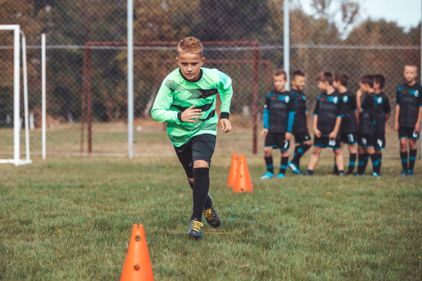 istock Young player in soccer jersey running between cones and ring ladder marker 1203069117