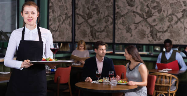 istock Attractive young waitress with serving tray welcoming in restaurant 1203069998