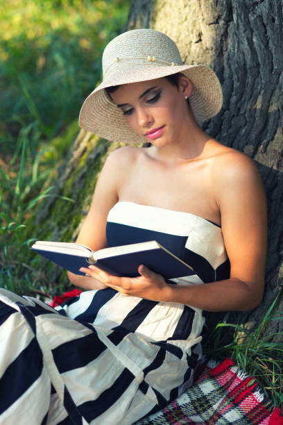 istock Woman reading book on the summer meadow 1203070278