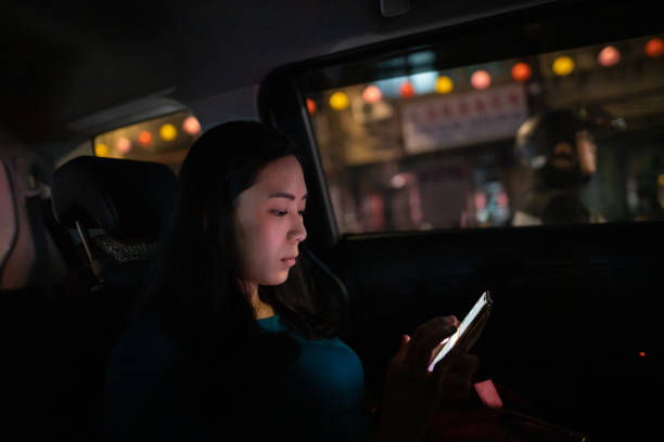 istock Young woman using smart phone in taxi 1203073459