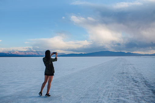 A lone woman taking photos of the dreamy landscape of the salt desert in Salta, Argentina.