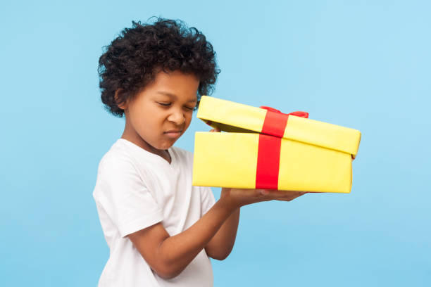 portrait of curious adorable little boy peeking inside gift box, unpacking present with funny inquisitive look - christmas child little boys peeking imagens e fotografias de stock