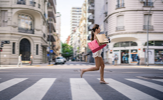 Beautiful woman running over a crosswalk in the city.