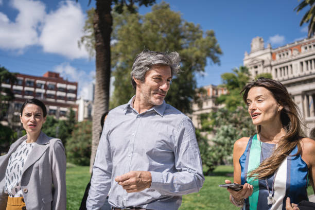 istock Cheerful coworkers returning together from work walking in the park 1203080746