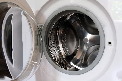 Window washing machine with the door open. Viewing window, door of the hatch assembled for the washing machine. Empty drum after washing.