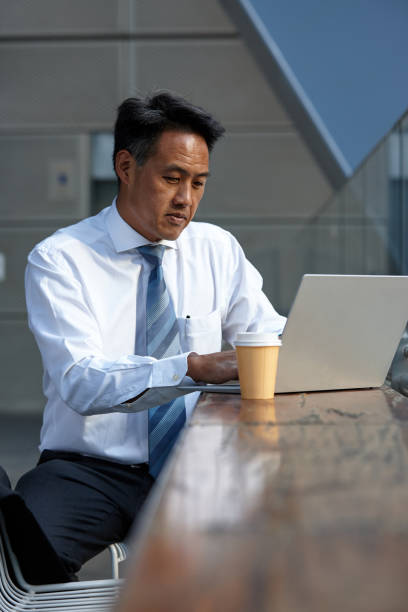 istock Australasian businessman working on laptop outside 1203082093