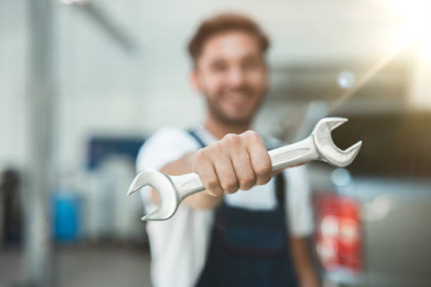 istock mechanic wearing uniform showing spanner in car service center 1203083190