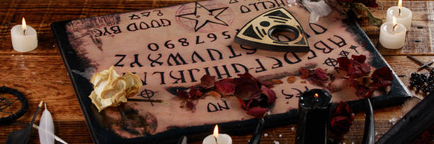 istock Talking board and planchette, also known as Ouija board, used for communicating with the dead and other spirits. The atmosphere of black art with candles and horns of the animal. 1203089588