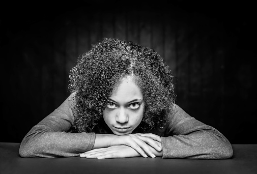 Black and white pretty young girl with big eyes and natural curls with her chin on hands