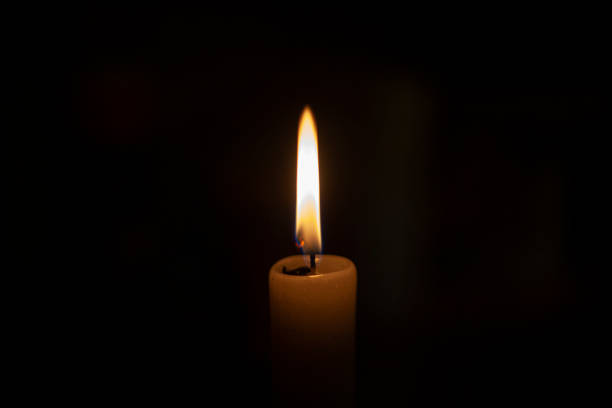 Candle flame in the dark. Candle flame in total darkness. A wax candle shines in flame. The wick burns. Church candle for prayer. Orthodox rite. ignorance stock pictures, royalty-free photos & images