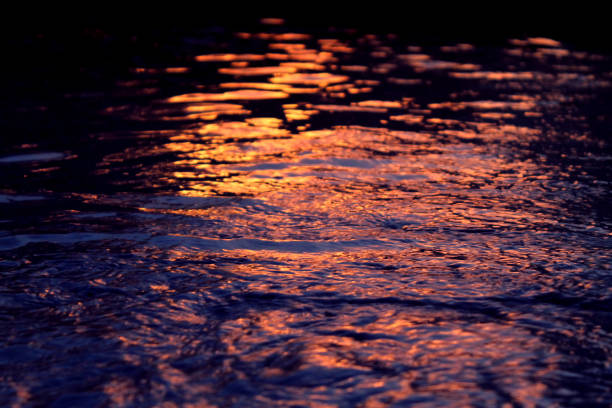 The warm tones of sunset reflecting off of rippled water.
