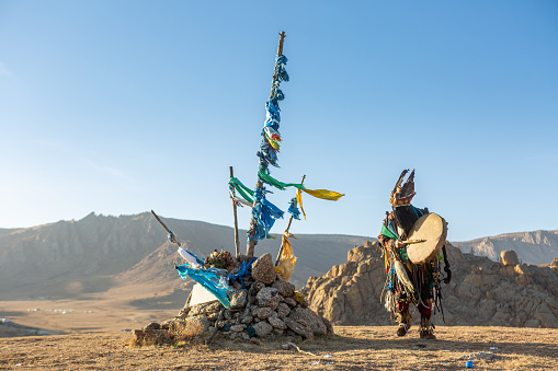 MONGOLIA - CIRCA NOVEMBER 2019 : mongolia shaman performed spiritual around Ovoo or Shaman's Shrine at the top of moutain and warm sunset