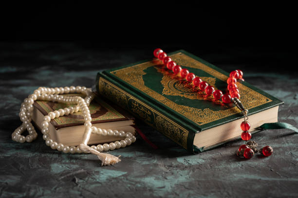 istock Islamic concept: The holy Quran and Tasbih (prayer beads beads) on dark background 1203114845